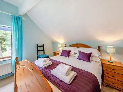 a bedroom with a large bed with purple and white pillows at Rhyblid Fach in Myddfai