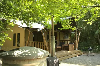 a house with a wooden deck with a tree at Luxury Safari Tent with Hot Tub in Ancient Woodland in Acton Scott