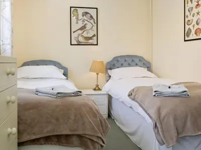 a bedroom with two beds and a night stand with a lamp at Crogen Coach House - Oqr in Llandrillo