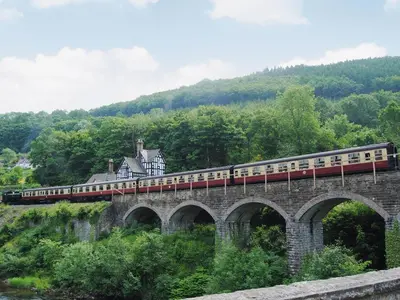 a train on a bridge with a house on it at Maesmor in Bala