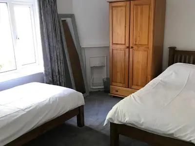a bedroom with two beds and a wooden cabinet at Barreg in Barmouth