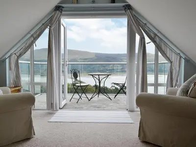an open door to a balcony with a table and chairs at Cae-Fadog Fach in Barmouth