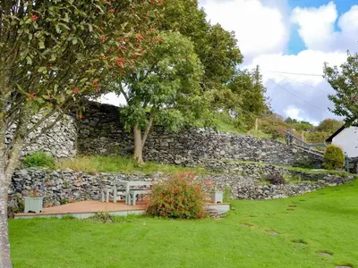 a stone wall with a table and chairs in a yard at Cae-Fadog Fach in Barmouth