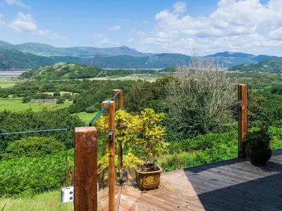 a wooden deck with a view of the mountains at Treetops in Fairbourne
