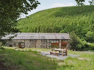 a stone house with a picnic table in front of it at Hendre Barn Mawr in Abergynolwyn