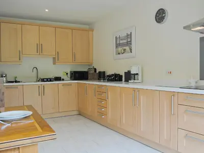 a large kitchen with wooden cabinets and a table at Hendre Barn Mawr in Abergynolwyn