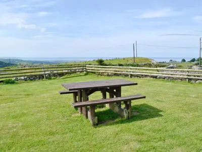 a picnic table sitting on top of a field at Ysgubor in Harlech
