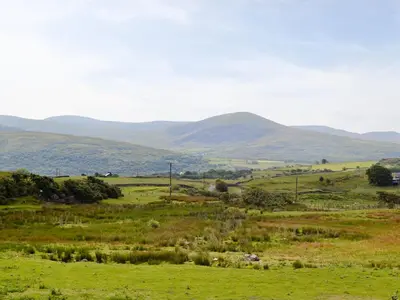 a green field with mountains in the distance at Ysgubor in Harlech