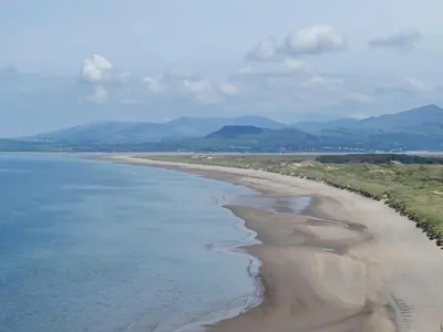 an aerial view of a beach with mountains in the background at Beudy Hen in Harlech