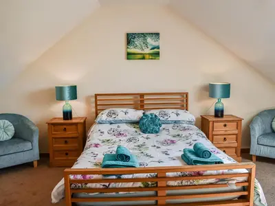 a bedroom with a bed and two chairs at Beudy Hen in Harlech
