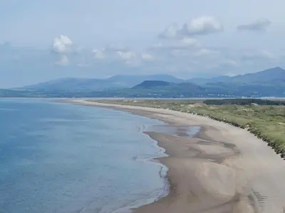 an aerial view of a beach with mountains in the background at Bod Eithin in Harlech
