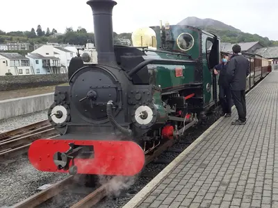 a green and red train sitting on the tracks at The Barn in Talsarnau