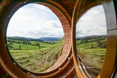 a circular window looking out at a green field at Foxes View in Rhayader