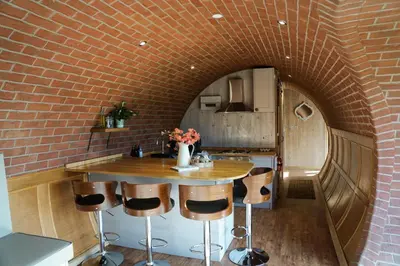 a brick wall in a kitchen with a table and stools at Foxes View in Rhayader
