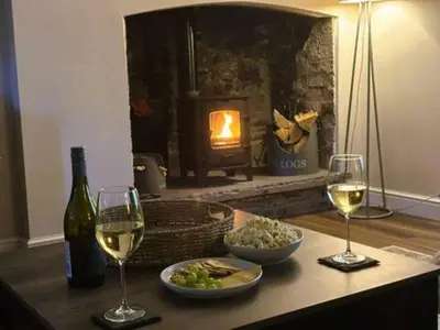 a table with two glasses of wine and a plate of food at The Cottage at Sychnant Farm in Talgarth