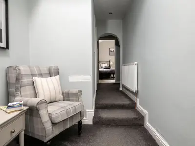 a hallway with a chair and a couch and a mirror at Fron Dderw in Bala
