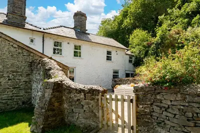 an old stone house with a wooden fence at Fron Dderw in Bala