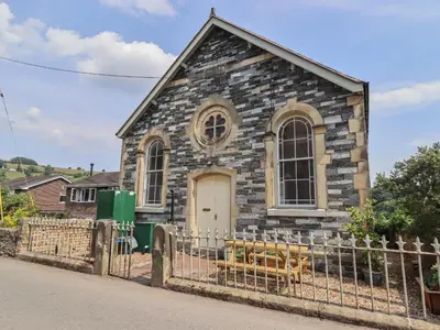 an old stone church with two dogs in front of it at Chapel House in Llangollen