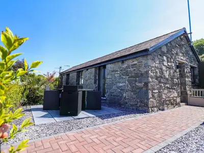 a stone building with two trash cans in front of it at Tan Llech in Harlech