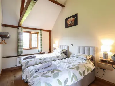 two beds in a room with white walls at Ysgubor Fachwen in Newtown