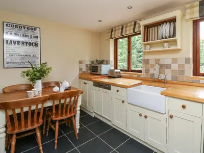 a kitchen with white cabinets and a table and a sink at Nant Glas in Llanwrda