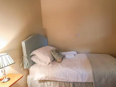 a small bedroom with a bed with white sheets and pillows at Nant Glas in Llanwrda