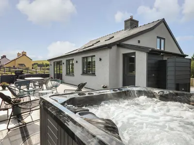 a hot tub on a patio with a house at Rhiwmynach in Aberystwyth