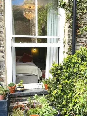 a bedroom with a bed in a window with potted plants at Sunny View in Aberystwyth