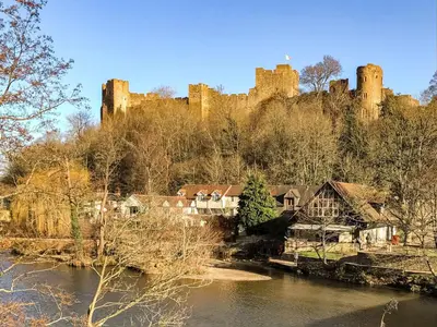 a castle sitting on top of a hill next to a river at The Loft At Callow Fold in Eaton
