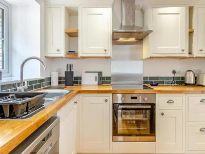 a kitchen with white cabinets and a sink at Y Beudy in Capel Bangor