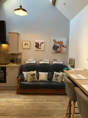 a living room with a black leather couch in a kitchen at Stunning cottage nestled under the Longmynd Hills. in Church Stretton