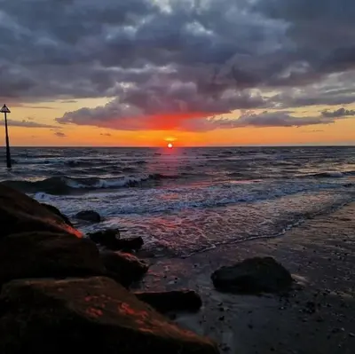 a sunset on a beach with the ocean at Idyllic, Luxurious Seaside Flat for 4. in Borth