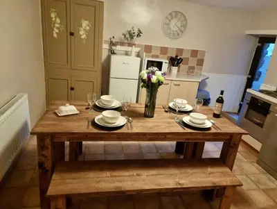 a kitchen with a wooden table with plates and glasses at Glasfor Cottage in Llwyngwril