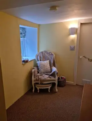 a chair sitting in a room with a window at Glasfor Cottage in Llwyngwril