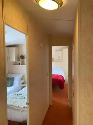 a small room with two beds and a mirror at 98Lemmington by the beach Ynyslas, Borth in Borth