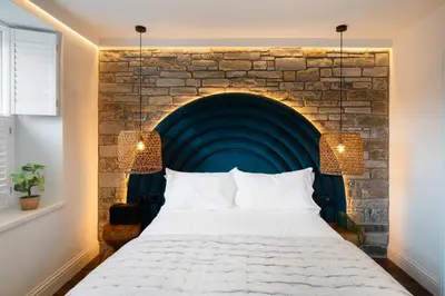 a bedroom with a large bed in front of a brick wall at Hive Townhouse in Aberaeron