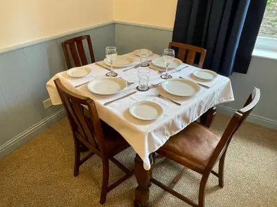 a table with plates and wine glasses on it at Glanywerydd Cottage in Barmouth