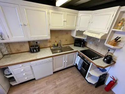 a white kitchen with white cabinets and a sink at Glanywerydd Cottage in Barmouth