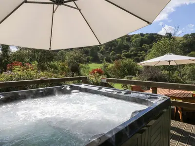 a hot tub with an umbrella on a deck at Penarth in Llandrindod Wells