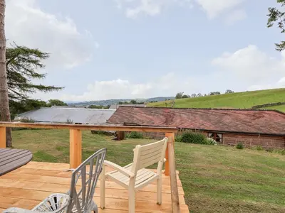 a deck with two chairs and a house at Y Caban in Llangollen