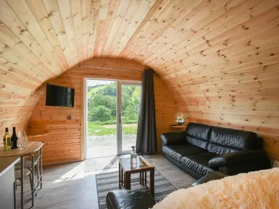 a living room with a black leather couch in a wooden room at Barcud Coch - Uk44539 in Hirnant