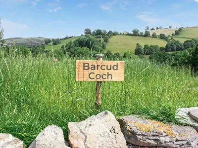 a sign in the middle of a field with a barroud coach at Barcud Coch - Uk44539 in Hirnant
