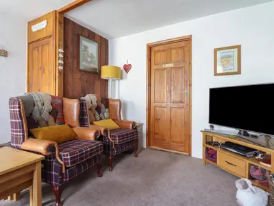 a living room with two chairs and a flat screen tv at Bodalaw in Trawsfynydd