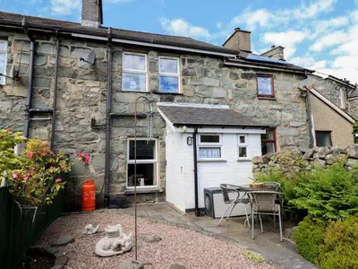 an old stone house with a table in front of it at Bodalaw in Trawsfynydd