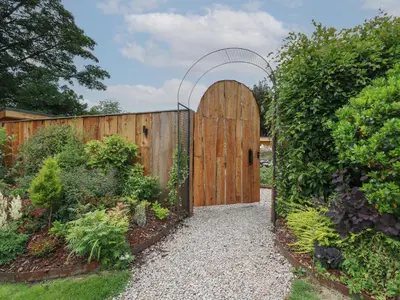 a wooden gate with an arch in a garden at Pansi in Welshpool