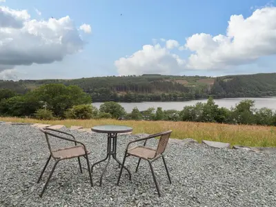 a table and two chairs sitting next to a lake at Llety Dewi in Oswestry