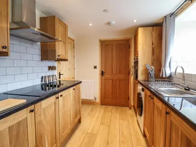 a kitchen with wooden cabinets and black counter tops at Llety Dewi in Oswestry