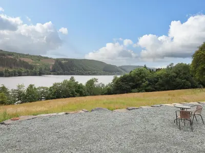 a table and chairs sitting on top of a gravel road near a lake at Llety Dewi in Oswestry