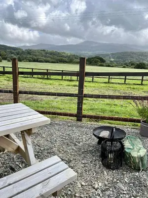 a picnic table and a grill next to a fence at Cwtch Cader Shepherds Hut in Llanelltyd