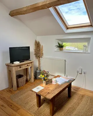 a living room with a wooden coffee table and a skylight at The Hayloft in Hereford